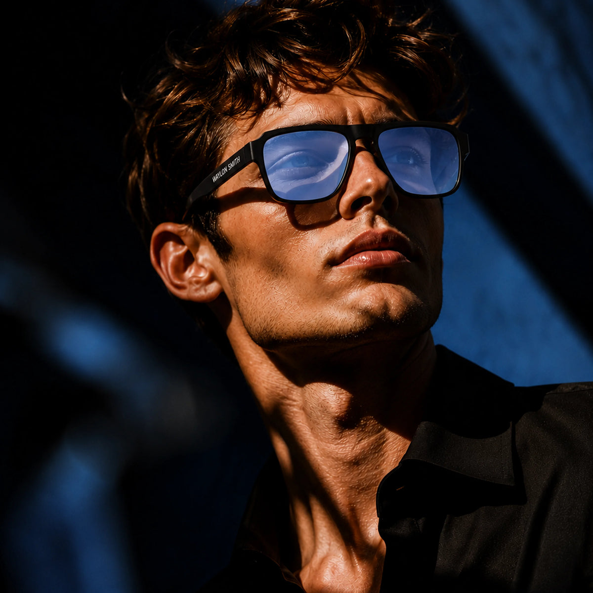Portrait of a man wearing black Waylon Smith sunglasses with blue lenses under dramatic side lighting