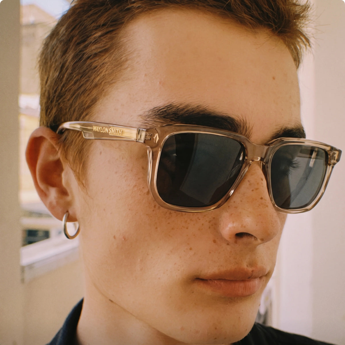 Close-up portrait of a man wearing transparent Waylon Smith sunglasses in champagne