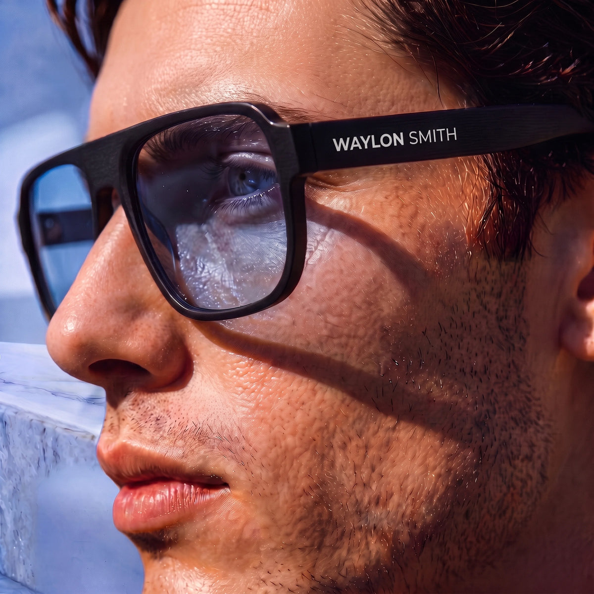 Extreme close-up profile of a man wearing black Waylon Smith sunglasses, showing the Waylon Smith wordmark on the temple