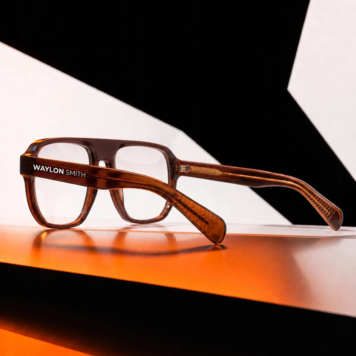 Waylon Smith sunglasses in amber tortoiseshell, studio product shot with dramatic geometric lighting, showing the Waylon Smith wordmark on the temple