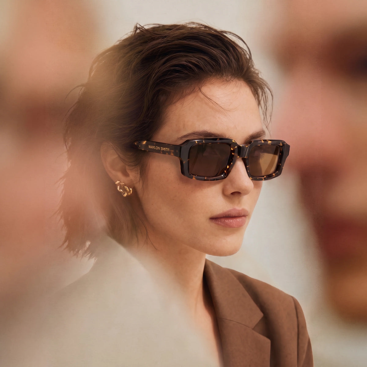 Woman in a beige coat wearing tortoiseshell Waylon Smith sunglasses, showing the Waylon Smith wordmark on the temple