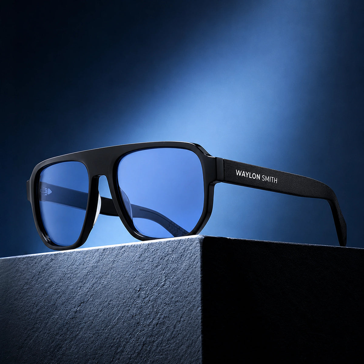Waylon Smith sunglasses in black with blue lenses, studio product shot on a stone pedestal with dramatic blue lighting