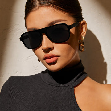 Woman with gold hoop earrings wearing black Waylon Smith Midnight Havana sunglasses in dramatic sunlit shadow portrait
