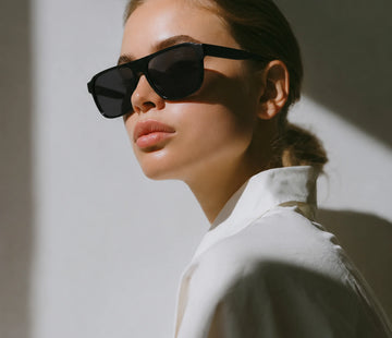Editorial portrait of a woman in a white shirt wearing black Waylon Smith sunglasses, dramatic side lighting