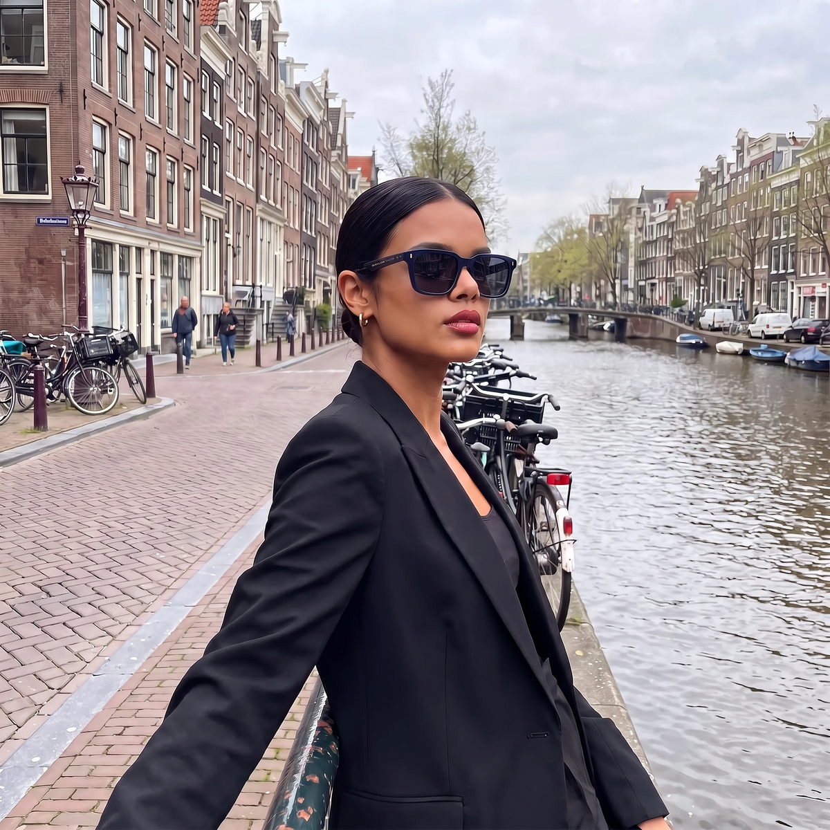 Woman wearing Waylon Smith Vinewood sunglasses in blue beside an Amsterdam canal with bicycles