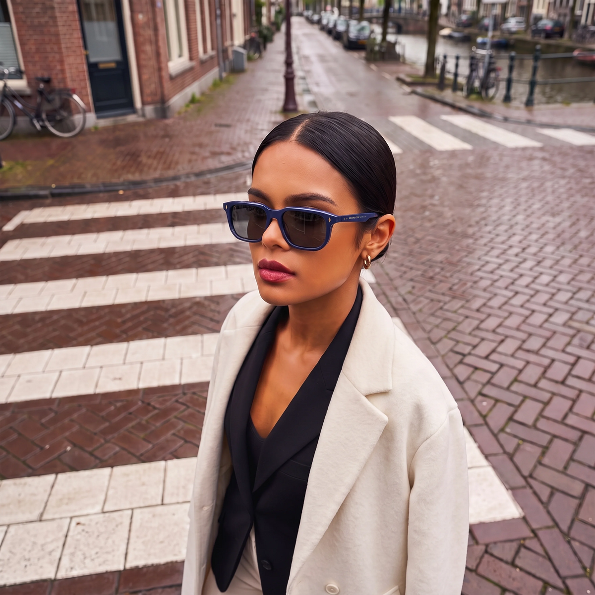 Woman wearing Waylon Smith Vinewood sunglasses in blue on an Amsterdam canal street